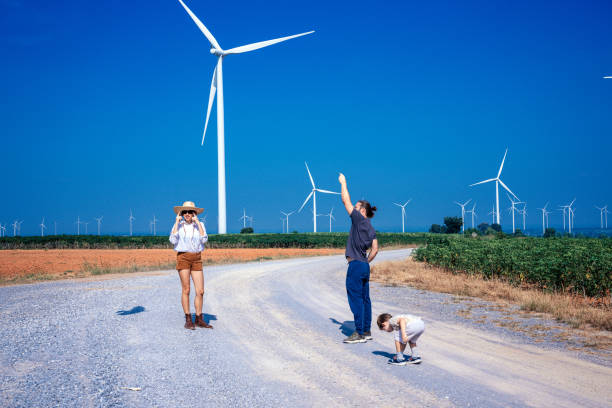 Father is teaching his son how to fly a kite at wind farm