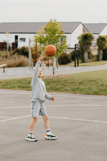 istock Happy boy throws ball into rim playing basketball on ground 2188144645
