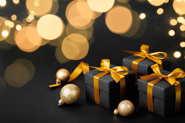 istock Black gift box with golden ribbon bow on black background 2188148407
