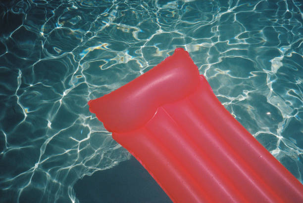 Pink inflatable raft floating gently on the rippled surface of a swimming pool, creating a serene summer atmosphere ideal for vacation, leisure, and relaxation in the sun