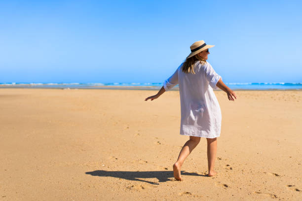 istock Beautiful mature woman walking on sandy beach 2188149864