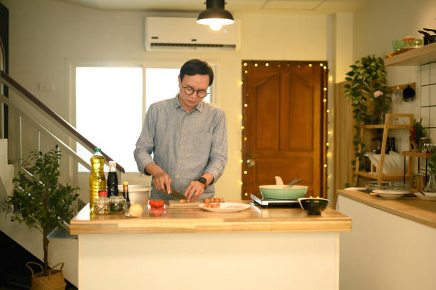 istock Middle aged man chopping ingredients on a wooden countertop in a kitchen 2188150138