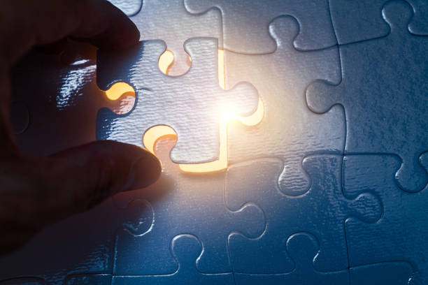 istock Man trying to put back missing jigsaw puzzle piece with light glow effect . Business strategy concept 2188151313