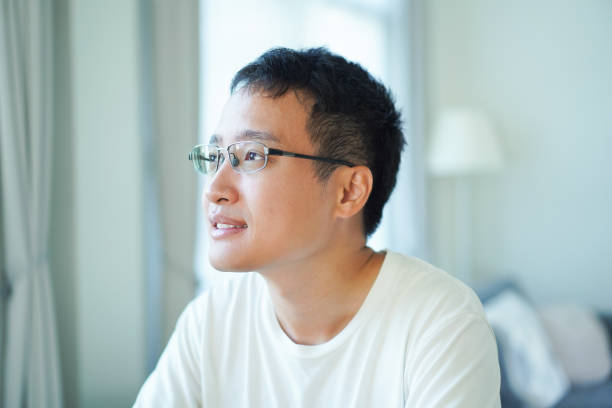 Asian man is sitting alone in living room at home.