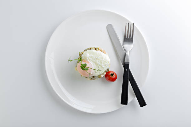 Russian salad Olivier served with poached egg on top in white plate