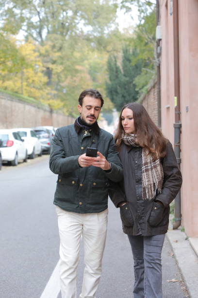 istock Tourists using smartphone app for gps navigation walking on sidewalk near brick wall and trees 2188168071