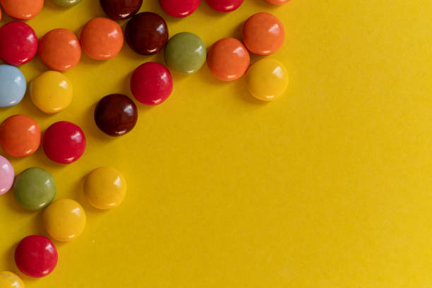 Colorful chocolates lined up on a yellow background