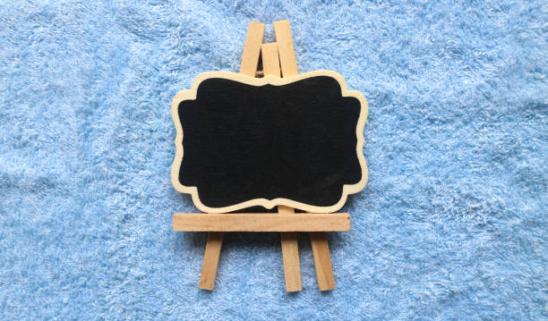 Wooden easel mini blackboard with faded chalk surface, isolated on blue background. Blank space for text