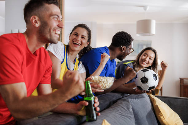 istock Friends cheering while watching a soccer game on TV at home 2188172501
