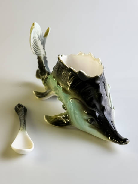 istock Caviar bowl with a spoon in the shape of a sturgeon on a white background. Specialized original dishes. 2188175936