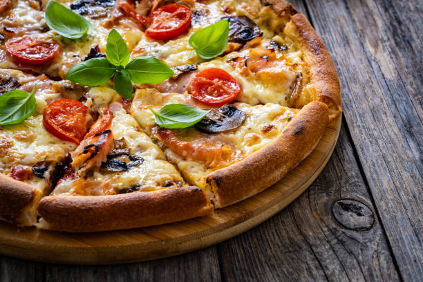 istock Circle vegetarian pizza with mozzarella cheese, mushrooms and tomatoes on wooden table 2188177721