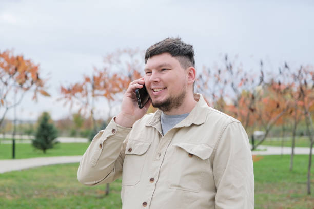 istock young caucasian man walking in the park and using smartphone 2188179653
