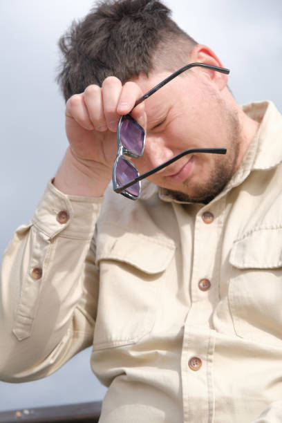 sad young man sitting in the park wiping his face