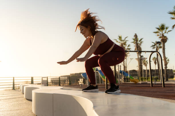 istock Curvy woman performing dynamic squat exercise at palm beach during sunset 2188182601
