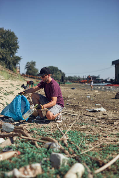 istock Environmental activist cleaning river shore from piled up trash. 2188183177