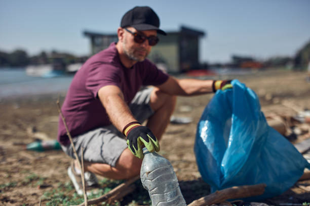 Environmental activist cleaning river shore from piled up trash.