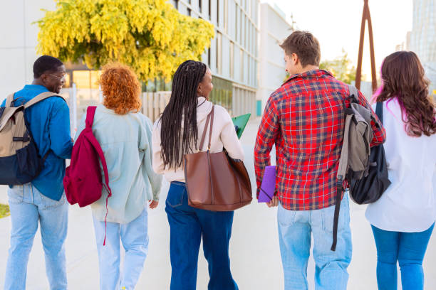 istock Group diverse students walking together with notebooks outdoors on a sunny day 2188184083