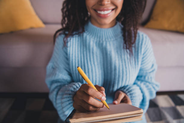 istock Young woman smiling while writing in a notebook at home during a cozy autumn day indoors 2188185749