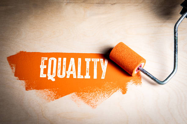 istock Equality. Orange paint and paint roller on a wooden texture background 2188188408