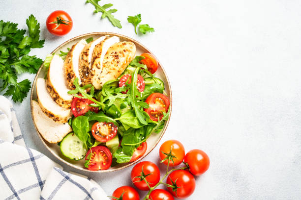 istock Green salad with grilled chicken meat at white table. 2188189946