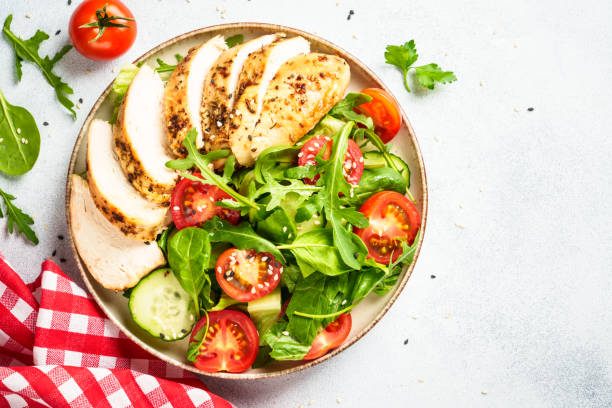 istock Green salad with grilled chicken meat at white table. 2188189969