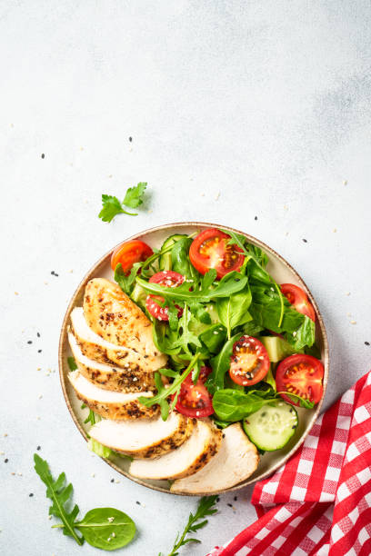 istock Green salad with grilled chicken meat at white table. 2188189972