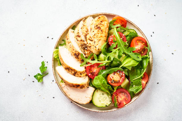 istock Green salad with grilled chicken meat at white table. 2188189987