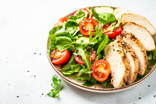 istock Green salad with grilled chicken meat at white table. 2188189996
