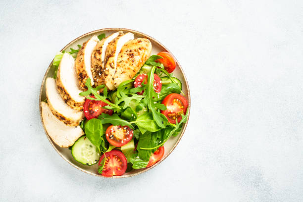 istock Green salad with grilled chicken meat at black table. 2188190054