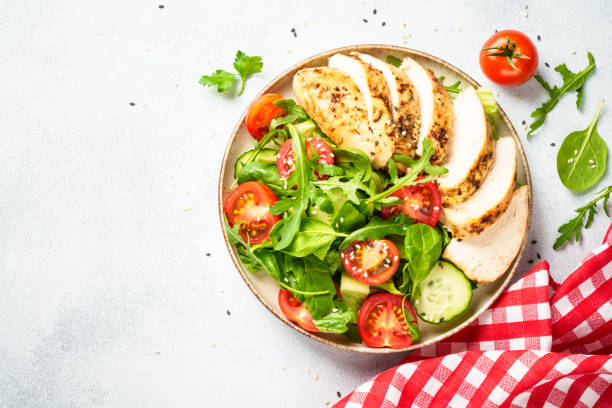 istock Green salad with grilled chicken meat at black table. 2188190059