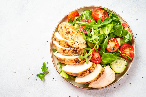 istock Green salad with grilled chicken meat at black table. 2188190085