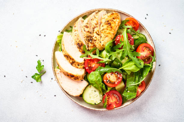 istock Green salad with grilled chicken meat at white table. 2188190086