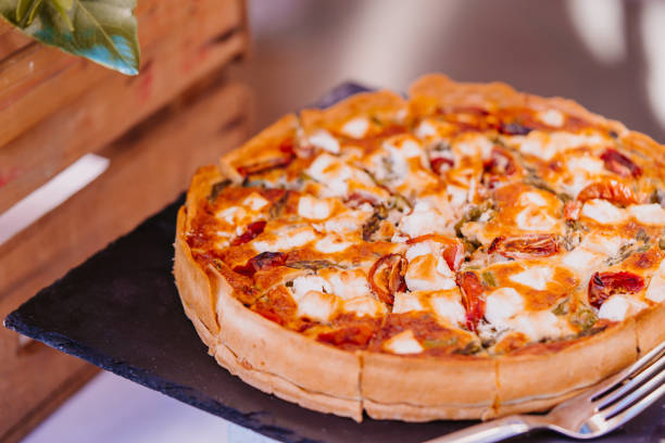 istock Delicious round quiche with tomatoes pre-sliced into portions is beautifully presented on a sleek black slate platter 2188203048