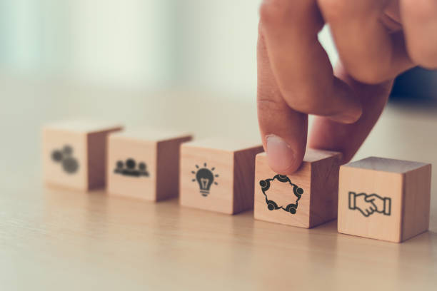 istock Strategic Collaboration and Innovation concept. A hand selecting a wooden block with a collaboration icon from a row of blocks depicting teamwork, ideas, and partnership, symbolizing business synergy. 2188206938