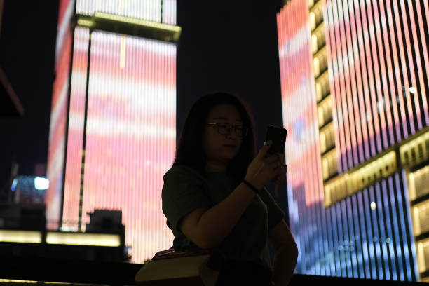 istock Woman using mobile phone with pink background on street at night 2188209547