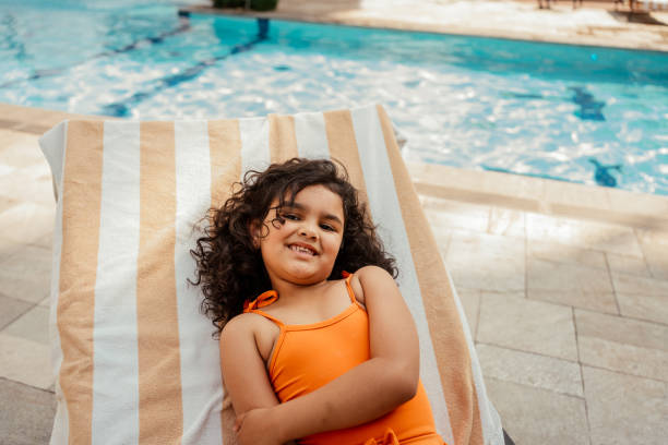 istock Child lying on sun lounger by poolside 2188210302