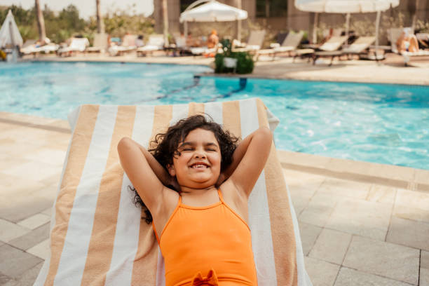 istock Child lying on sun lounger by poolside 2188210306