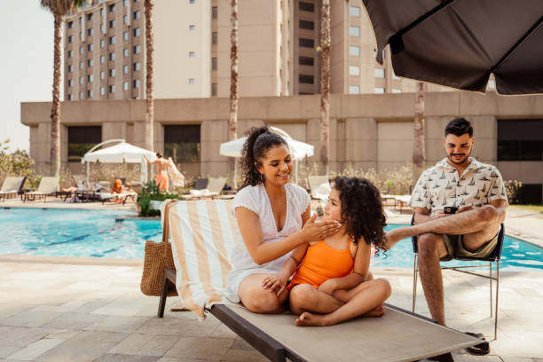 Mother putting sunscreen on her daughter before going into the pool