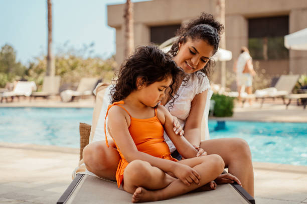 istock Mother putting sunscreen on her daughter before going into the pool 2188210321