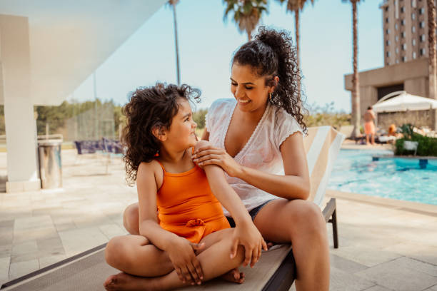 istock Mother putting sunscreen on her daughter before going into the pool 2188210336