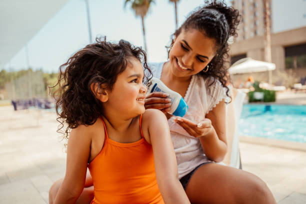 istock Mother putting sunscreen on her daughter before going into the pool 2188210352