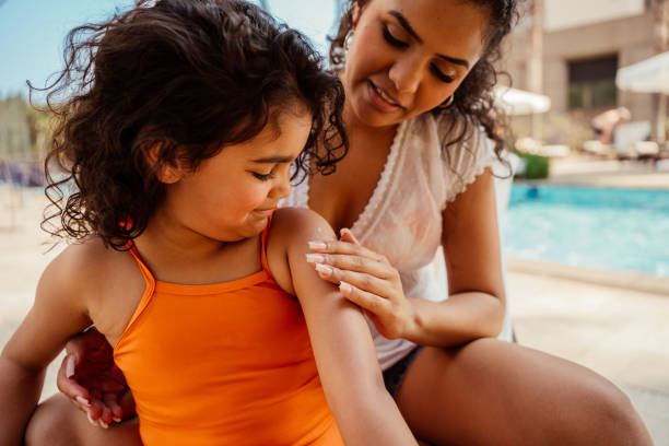 istock Mother putting sunscreen on her daughter before going into the pool 2188210353