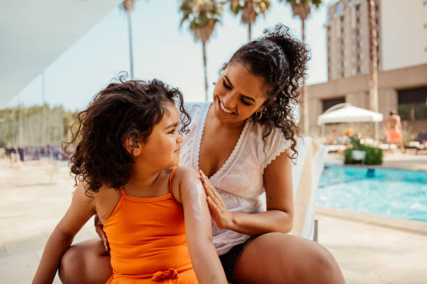 Mother putting sunscreen on her daughter before going into the pool