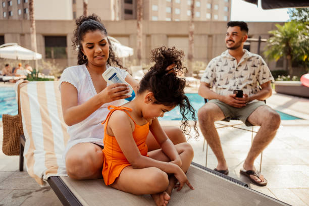 Mother putting sunscreen on her daughter before going into the pool
