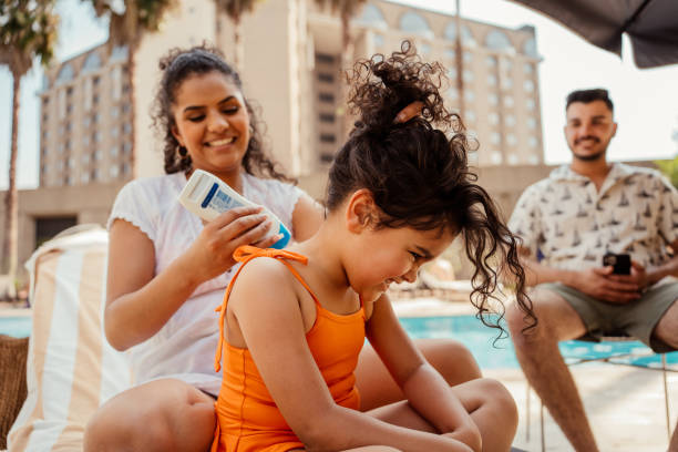 istock Mother putting sunscreen on her daughter before going into the pool 2188210370