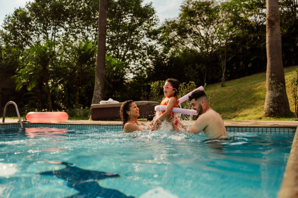 Parents holding their daughter who jumps into the pool