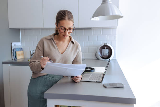 istock Young woman with documents and laptop following online courses 2188211635