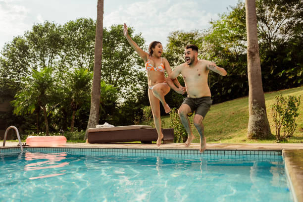 istock Couple jumping into pool at luxury hotel 2188211671