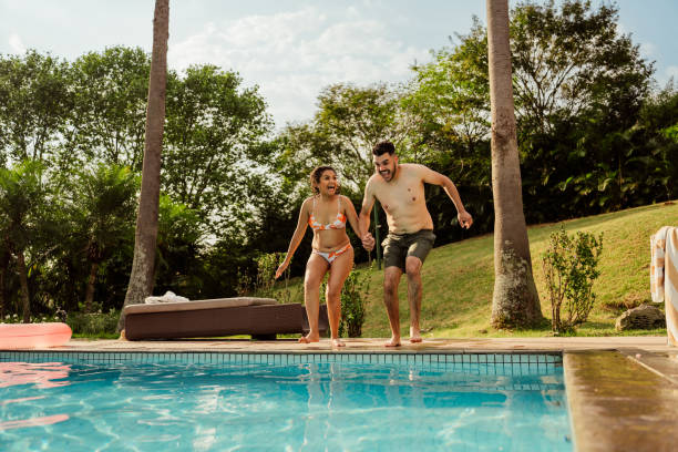 istock Couple jumping into pool at luxury hotel 2188211804