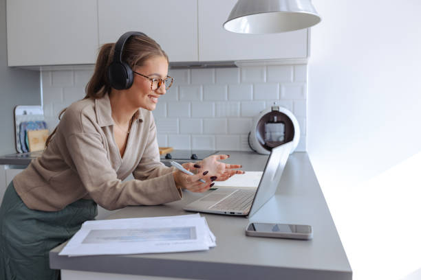 istock Young female student with headphones attending virtual class via laptop 2188211949